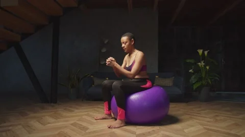 Fit female doing basic bounce exercise on fitball 動画素材 143307578
