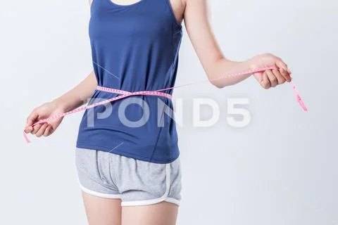 Fit fitness girl measuring her waistline with measure tape Stock Photos