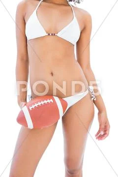 Fit girl in white bikini holding american football Stock Photos