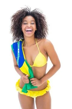 Fit girl in yellow bikini holding brazil flag smiling at camera Stock Photos