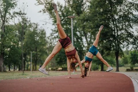 Fit girls confidently performing 360 degree flips, showcasing their strength and Stock Photos
