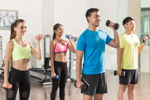 Fit handsome man smiling while exercising bicep curls during group workout Stock Photos