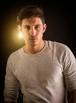 Fit handsome young man standing confident in casual clothes with light behind Stock Photos