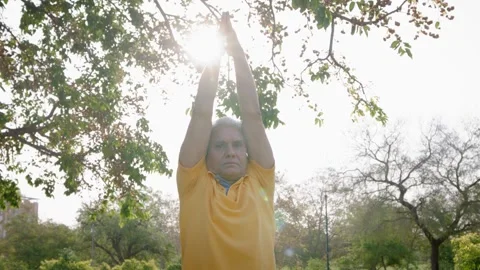 Fit Indian Grey Haired old Man Performing Yoga asana against sunlight Outdoors. Stock Footage 249843592