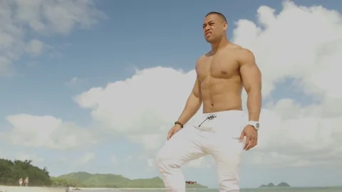 Fit man blinded by the sun squinting in the sunlight on the beach 動画素材 83689966