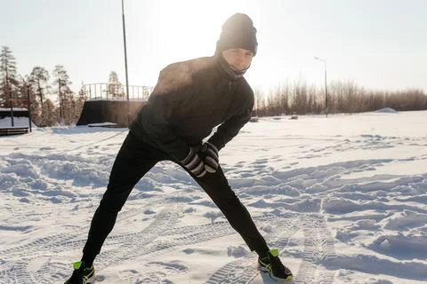 Fit man does stretching exercises before running outdoors, looking into the Stock Photos