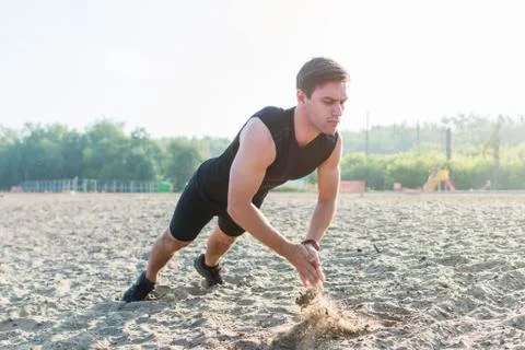 Fit man doing clapping push-ups during training exercise workout on beach in Stockfoto's