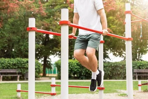 Fit man doing dips on parallel bars at an outdoor sports ground. Bodyweight.. Foto stock