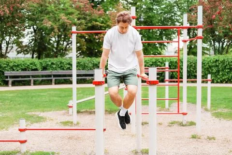 Fit man doing dips at a public outdoor gym. Enjoying an active lifestyle, b.. Stock Photos