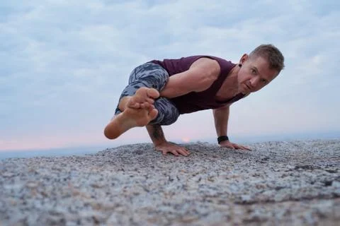 Fit man doing the eight angle pose on a rock Stock Photos