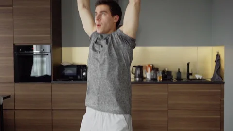Fit man doing jumping jacks at home Stock Footage 128763893