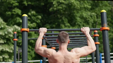 Fit man doing pull ups on sportsground Stock Footage 244373184