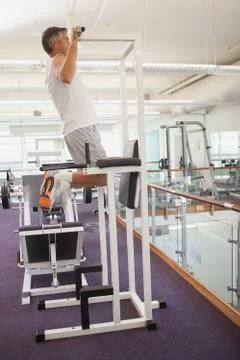 Fit man doing pull ups in fitness studio Stock Photos