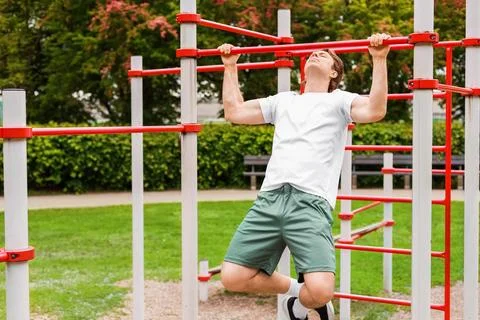 Fit man doing pull-ups at a public sports ground. Outdoor fitness, bodyweig.. Stockfoto's
