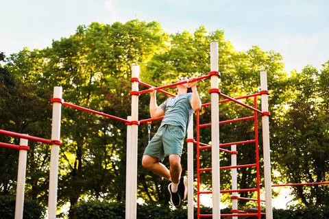 Fit man doing a pullup exercise during an outdoor street workout. Physical .. Stock Photos