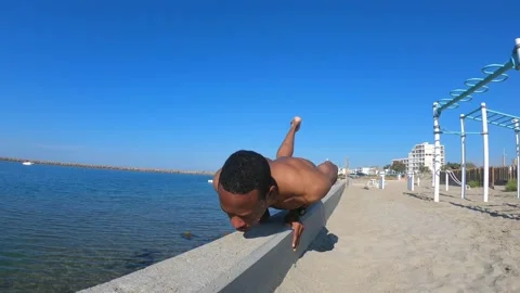 Fit man doing push ups on the beach on a sunny summer day Video stock 155709456