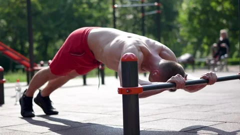 Fit man doing push ups behind the bar outdoors Stock Footage 245267947