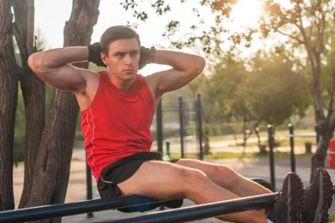 Fit man doing sit ups on parallel bars outdoor fitness station Foto stock