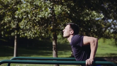 Fit man doing triceps dips on parallel bars at park exercising outdoors Stock-Footage 83676099