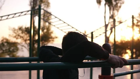 Fit man doing triceps dips on parallel bars at park exercising outdoors in the 動画素材 98202805