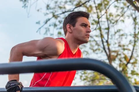Fit man doing triceps dips on parallel bars at park exercising outdoors Stock Photos