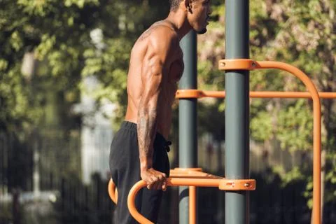 Fit man doing triceps dips on parallel bars at park Stock Photos