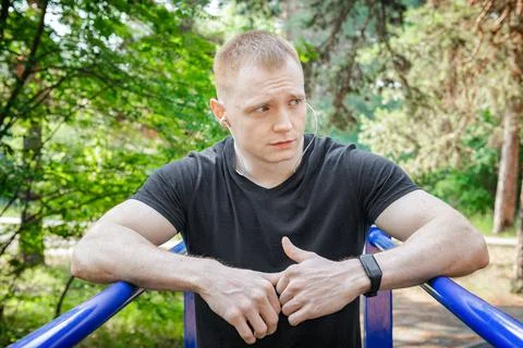 Fit man doing triceps dips on parallel bars at park exercising outdoors. Stock Photos