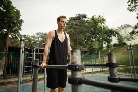 Fit man doing triceps dips on parallel bars at park exercising outdoors Stock-Fotos