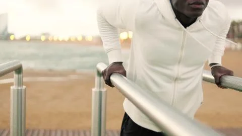 Fit man doing triceps dips on parallel bars outdoors, sports motivation, ac.. Stock Photos