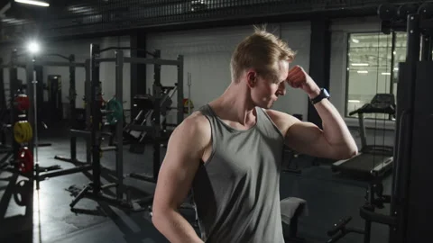 Fit Man Flexing Biceps and Showing Muscles in Gym Stock Footage 339885151