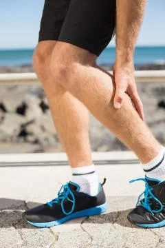 Fit man gripping his injured calf muscle Stock Photos