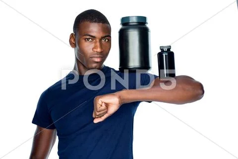 Fit man holding bottles with supplements on his biceps Stock Photos