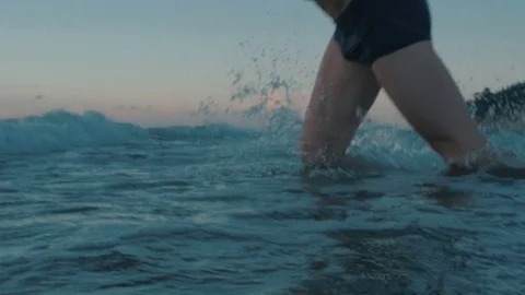 Fit man jumping in ocean in slow motion at sunset Video stock 83781585