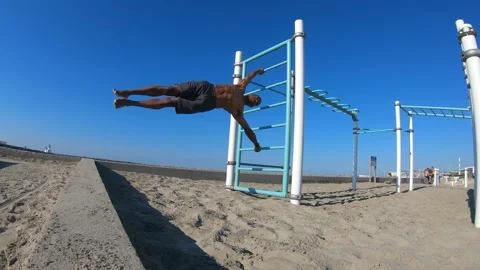 Fit man performing a human flag on the beach on a sunny summer day Stock Footage