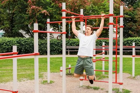 Fit man performing pull-ups on a bar at an outdoor sports ground. Bodyweigh.. Stock Photos