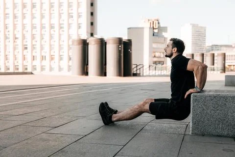 Fit man pushing from stone cube. Morning workout outdoors. Black sportswear. Man Stock Photos