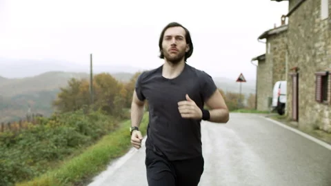 Fit man running along a quiet street in Tuscany, with soft overcast lighting. Wi Stock Footage 199455385