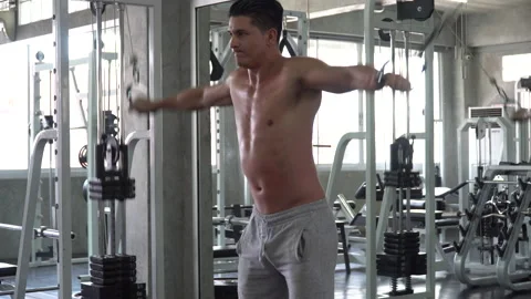 Fit man shirtless exercises with  rowing machine in fitness club  . Muscular Stock Footage 162810683