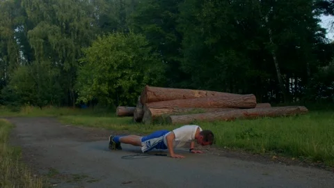 A fit man shows strength doing pushups in various outdoor settings Vídeos de archivo 314347137