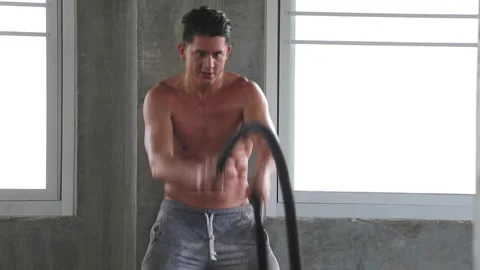Fit man training workout with battle rope exercise in gym Stock Footage 246101859