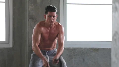 Fit man training workout with battle rope exercise in gym Stock Footage 246101865