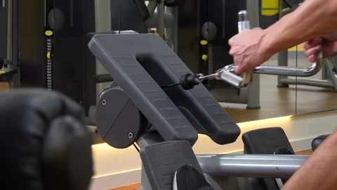 A fit man trains on a rowing machine in a gym - closeup Stock Footage 87929266