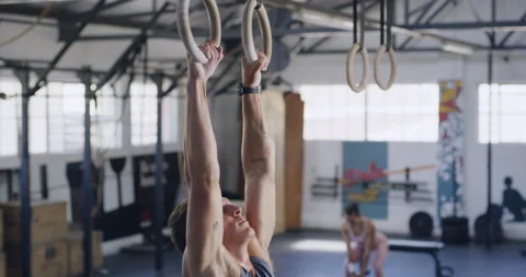 Fit man using gymnastic rings for pull ups for training exercise in a gym Stock Footage 200924672