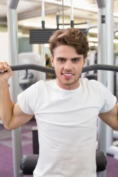 Fit man using weights machine for arms smiling at camera Stock Photos