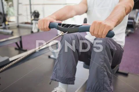 Fit man working out on rowing machine Stock Photos