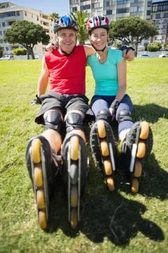 Fit mature couple wearing roller blades on the grass Stock Photos