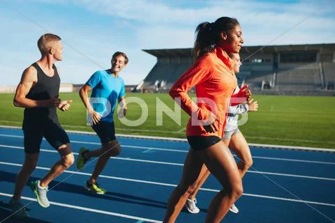 Fit men and women running on a race track Stock Photos