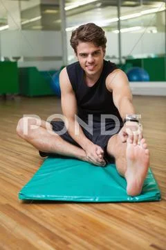 Fit smiling man warming up in fitness studio Stock Photos