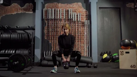 Fit woman doing squats with kettlebell in gym Stock Footage