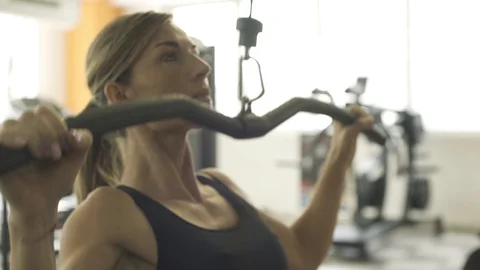 Fit woman exercising with a lat pulldown machine Stock Footage 128585169